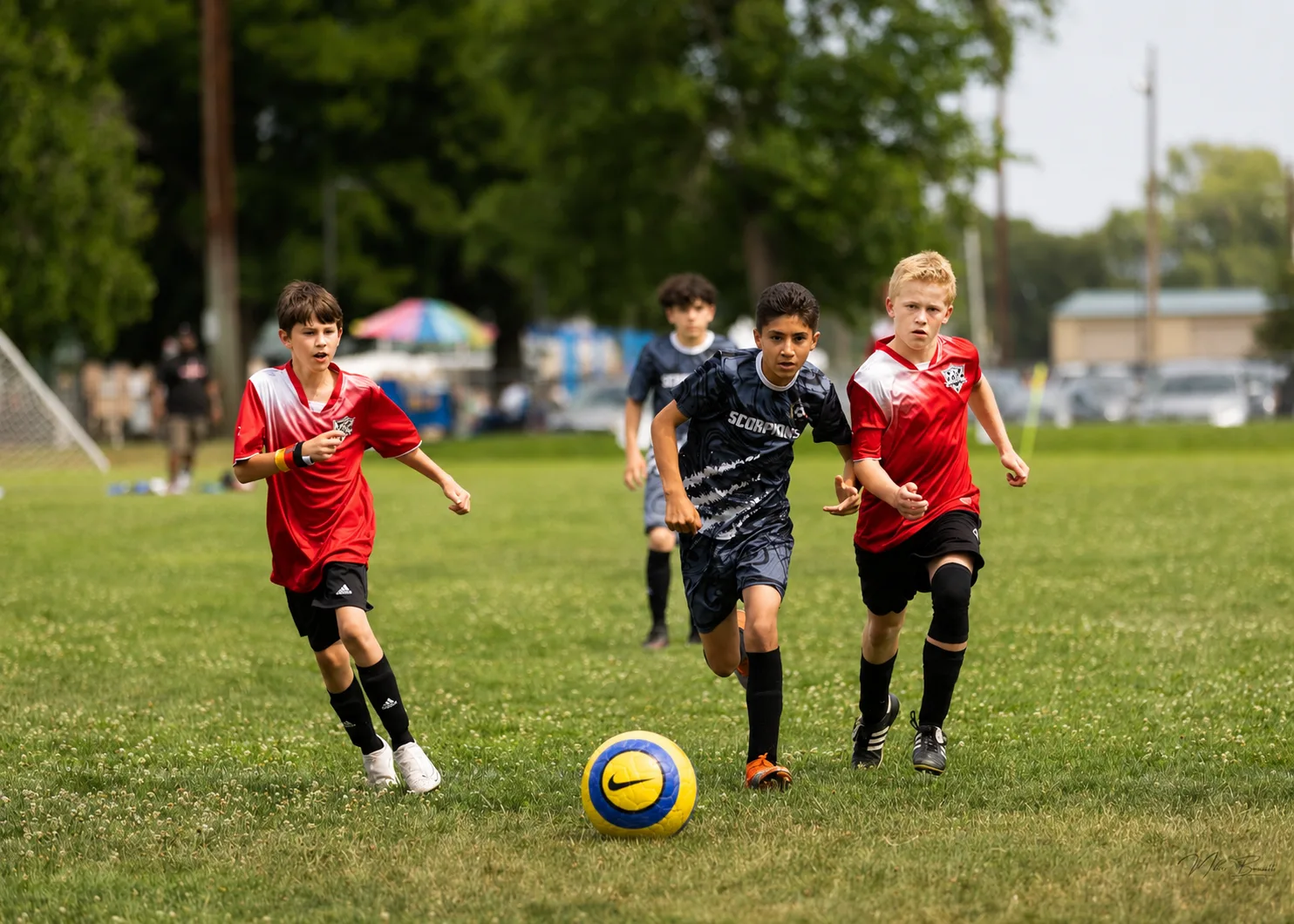 Youth soccer players chasing the ball across the field